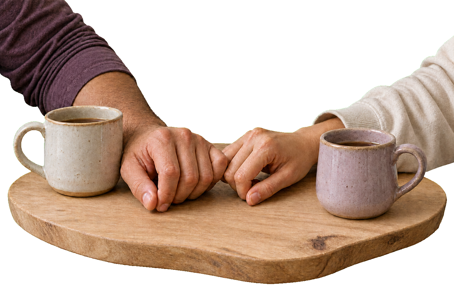 Two people gently link little fingers over a pair of mugs